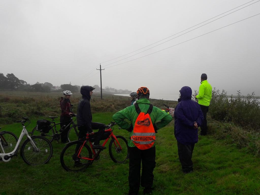 Group of damp cyclists looking over the river
