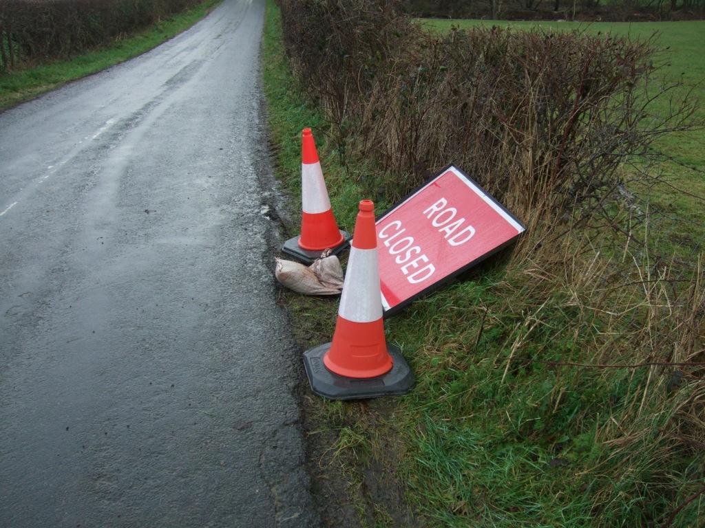 Road closed sign lying in the hedge